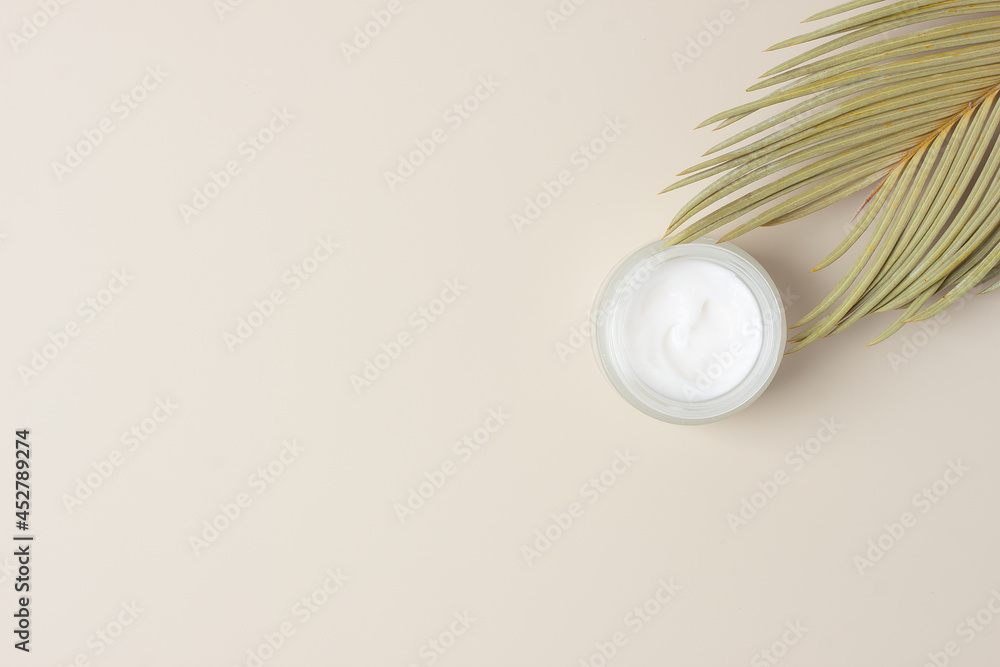 Jar of cosmetic cream with palm leaf on pastel beige background. Flat lay, copy space Jar of cosmetic cream with palm leaf on pastel beige background. Flat lay, copy space