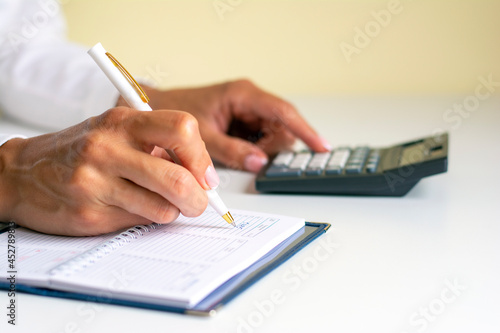 Close-up of the hands of a woman writing in a notebook