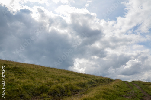 Beautiful mountain landscape in the summer. Green grass, rural road and fantastic sky on background. Carpathian Mountains, Ukraine