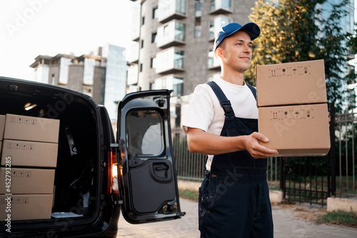 In the form of a courier, a man of Caucasian appearance works in express delivery. The transport company delivers the goods in a package. The entrepreneur is young in his business. photo