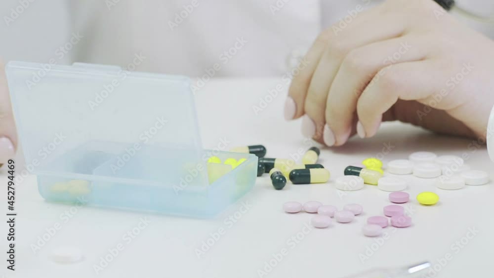 Close-up of a pillbox with different tablets. A person's hands put pills in a pillbox