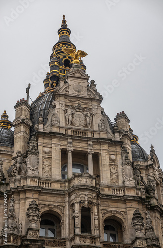 Antwerpen, Belgium - August 1, 2021: Top facade of 19th century palace which is now a business complex on corner of Leysstraat and Kipdorpvest. Sculptures, frescos, and golden eagle. © Klodien