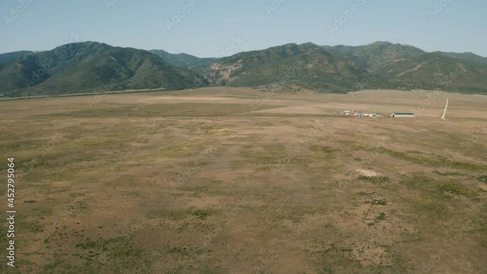 Aerial-Flying over barren valley to cars traveling on highway and distant mountain canyon Aerial-Flying over barren valley to cars traveling on highway and distant mountain canyon