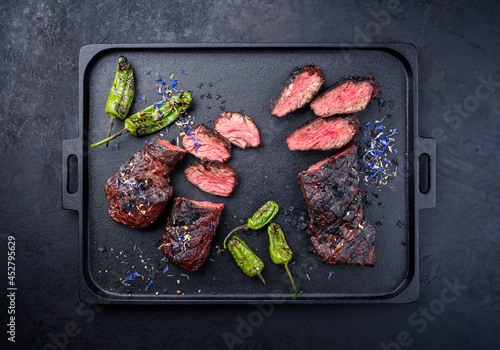 Modern style traditional barbecue wagyu onglet steak with green chili and spices served as top view on a design cast-iron tray