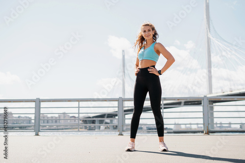 Healthy lifestyle, sports activities in the city. The trainer is engaged in fitness on the street. A smart watch on your hand for counting calories. A sporty woman does exercises in the open air.