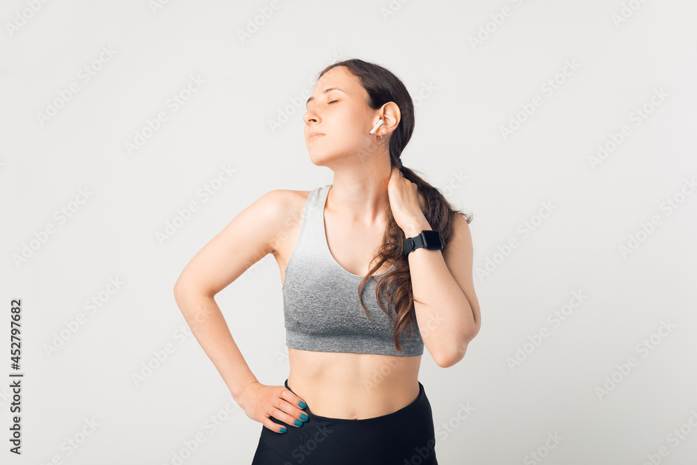 Fototapeta premium Young lady wearing sportswear is taking a break because of her neck aches.