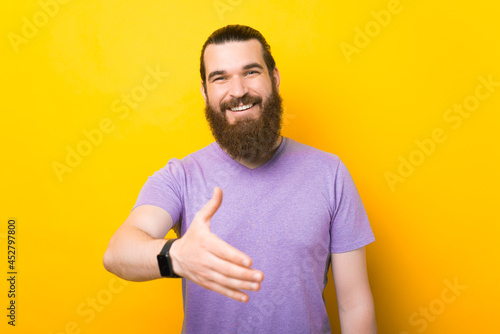 Young caucasian bearded man is giving his hand for a handshake.