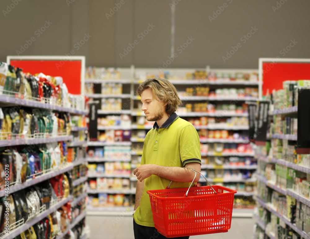 Young man shopping in supermarket, reading product information