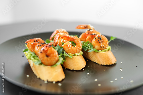 Bruschetta with shrimp, sprinkled with sesame seeds on a plate, buffet with seafood