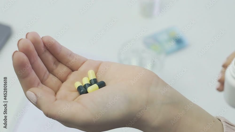Close-up of an unrecognizable woman, a patient, holding a jar of pills and pouring it into her hand Close-up of an unrecognizable woman, a patient, holding a jar of pills and pouring it into her hand