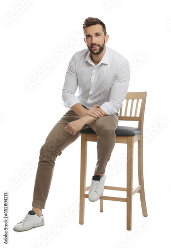 Handsome man sitting on stool against white background