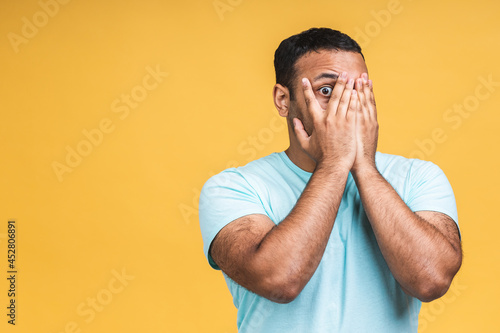 Surprised amazed african american indian man guy in casual isolated over yellow background studio portrait. People lifestyle concept. Mock up copy space. Keeping mouth open. photo
