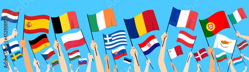 Close up of hands rising up 27 European Union member countries flags on blue background