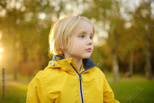 Portrait of little boy having fun during stroll in the public park at sunny autumn day. Active family time on nature. Hiking with little kids.