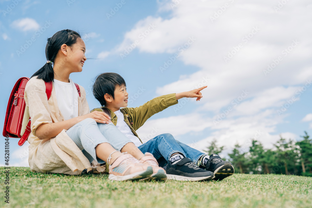 芝生に座る小学生(指差す)
芝生に座る小学生(指差す)