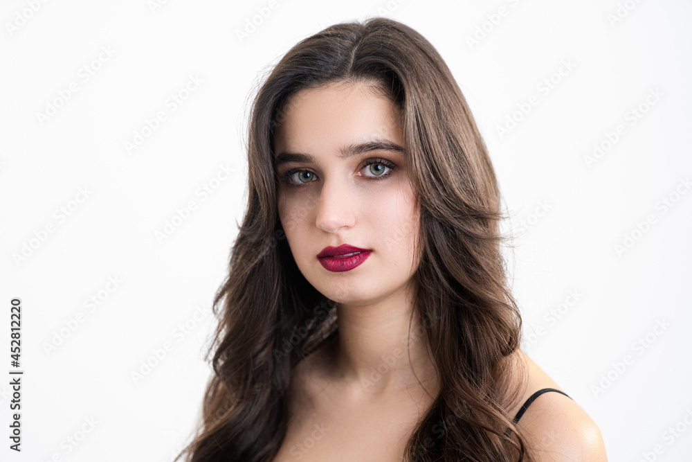 The girl with make-up and styling looks into the camera. Photo of a girl on a white background.