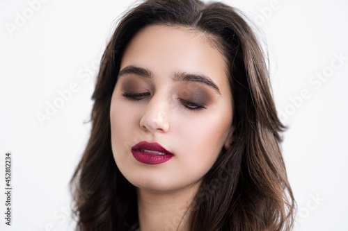 Girl's face close up. Studio makeup. Bright lips. Thick and dark eyebrows.