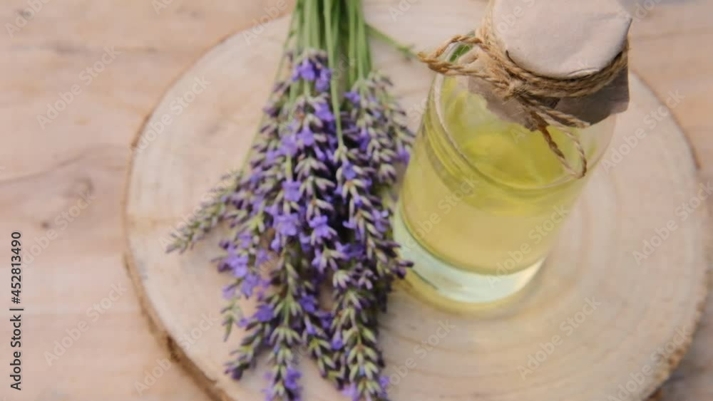 Lavender oil in a glass bottle and lavender sprigs on a wooden cut on a wooden table.Organic pure essential oil. Natural natural bio cosmetics. High quality 4k footage Lavender oil in a glass bottle and lavender sprigs on a wooden cut on a wooden table.Organic pure essential oil. Natural natural bio cosmetics. High quality 4k footage