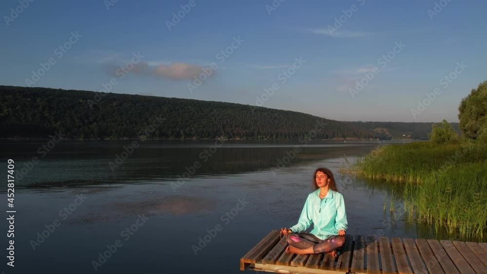 Beautiful young woman performing a spiritual yoga pose on the wooden pier. Sunrise Beautiful young woman performing a spiritual yoga pose on the wooden pier. Sunrise