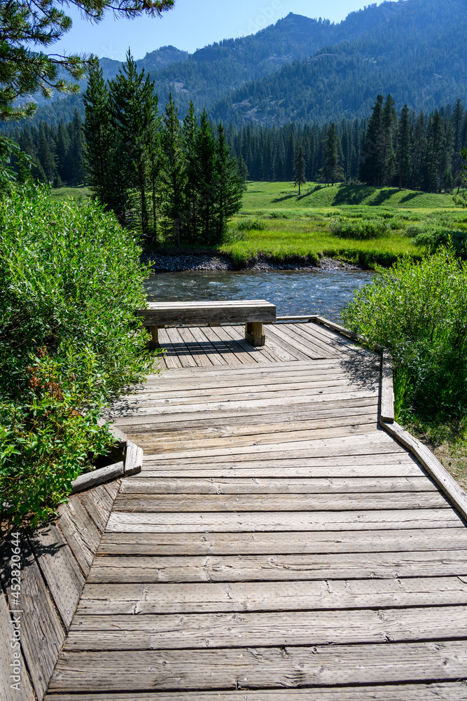Tranquil outdoor setting with wood bench for contemplation on Soda Butte Creek, Yellowstone National Park, USA
