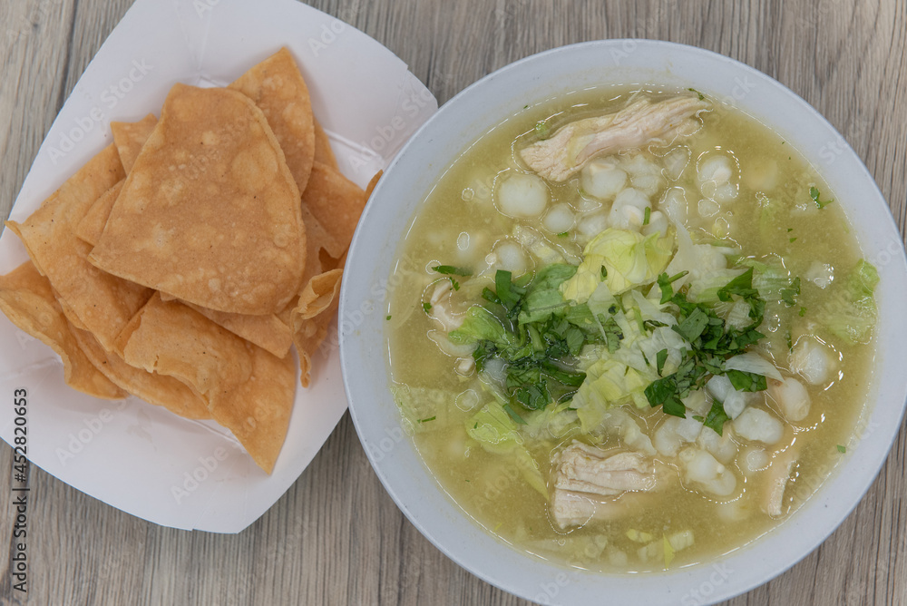 Overhead view of hearty bowl of chicken pozole soup hot from the kitchen and served with a side order of chips Overhead view of hearty bowl of chicken pozole soup hot from the kitchen and served with a side order of chips