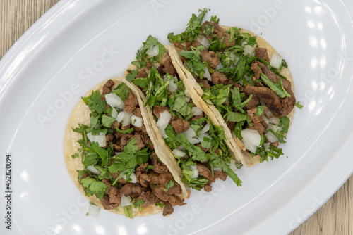 Overhead view of hearty side order of carne asada steak street tacos filled with meat, cilantro, and onions photo