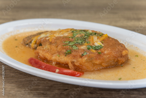 Hearty appetizer of chili relleno smothered in wet sauce with a slice of pepper on the plate