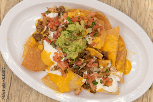 Fotografi Overhead view of hearty plate of nachos smothered with melted cheese, pico de ga