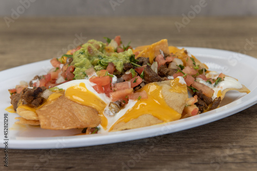 Foto Hearty plate of nachos smothered with melted cheese, pico de gallo, and sour cre
