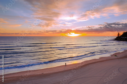 Person on a beach watching the ocean waves at surise photo