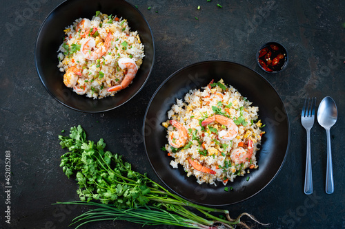 Asian fried rice with shrimp on the black dish in Thai. Prepared in wok. Top view.