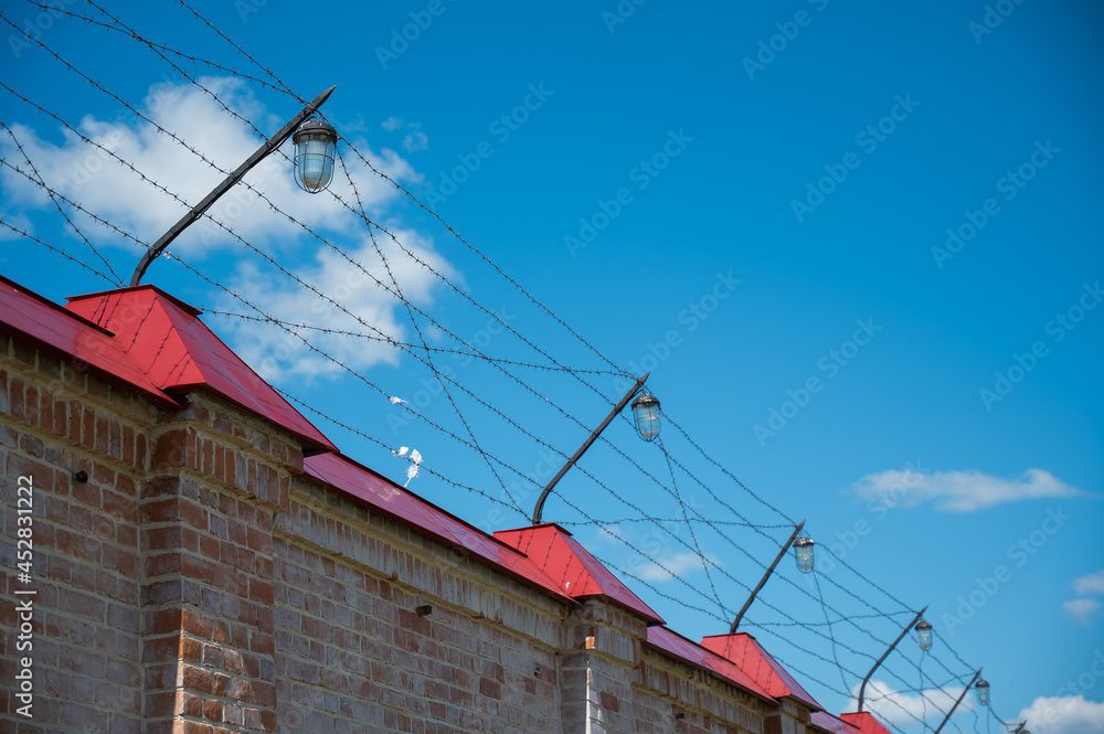 Barbed wire on the fence of the prison against the blue sky Barbed wire on the fence of the prison against the blue sky