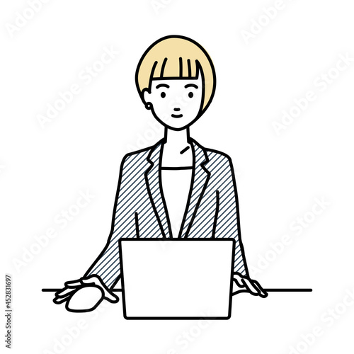 デスクで座ってPCを使っているスーツの女性