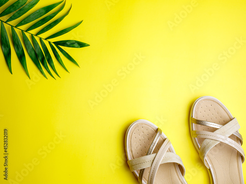 Stylish beige leather summer comfortable women's sandals on bright yellow and blue paper background. Concept of recreation by sea and summer vacation. Flat lay, top view, copy space. photo