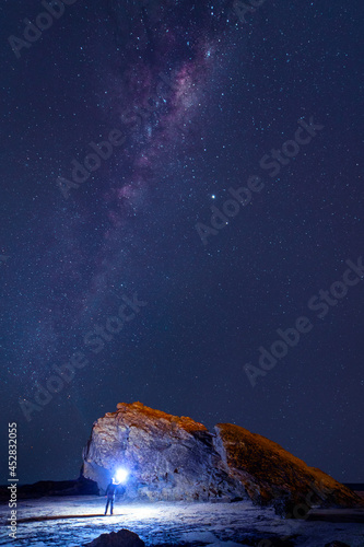 Person holding a torch with Milkyway in the sky over Currumbin Rock  Gold Coast.