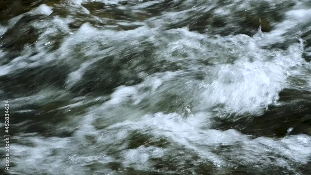 A stream of water with foam and a rocky bottom of a mountain river. A stream of water with foam and a rocky bottom of a mountain river.