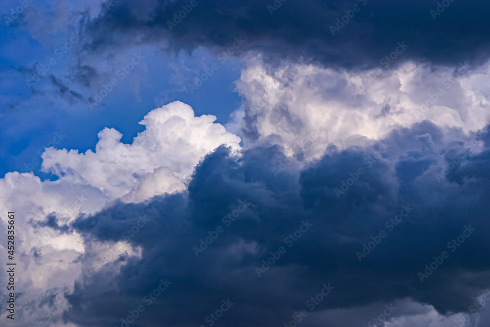 Dark grey and billowing white clouds against a blue sky
