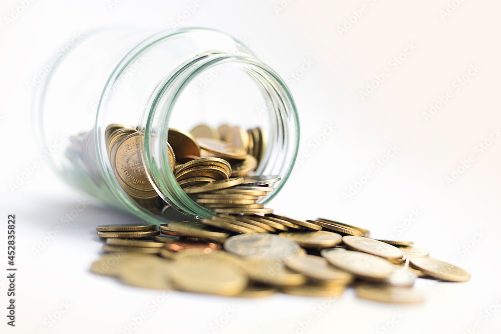 Coin into a glass jar isolated on white background. Financial business investment - Saving money concept Coin into a glass jar isolated on white background. Financial business investment - Saving money concept
