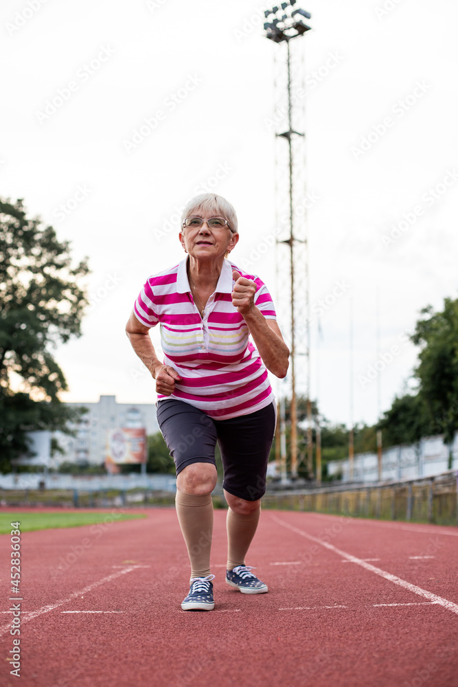 older woman doing gymnastics and running in the stadium, person running older woman doing gymnastics and running in the stadium, person running
