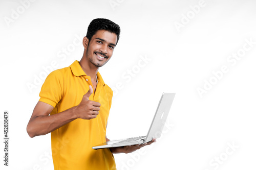 Young indian man using laptop on white background.