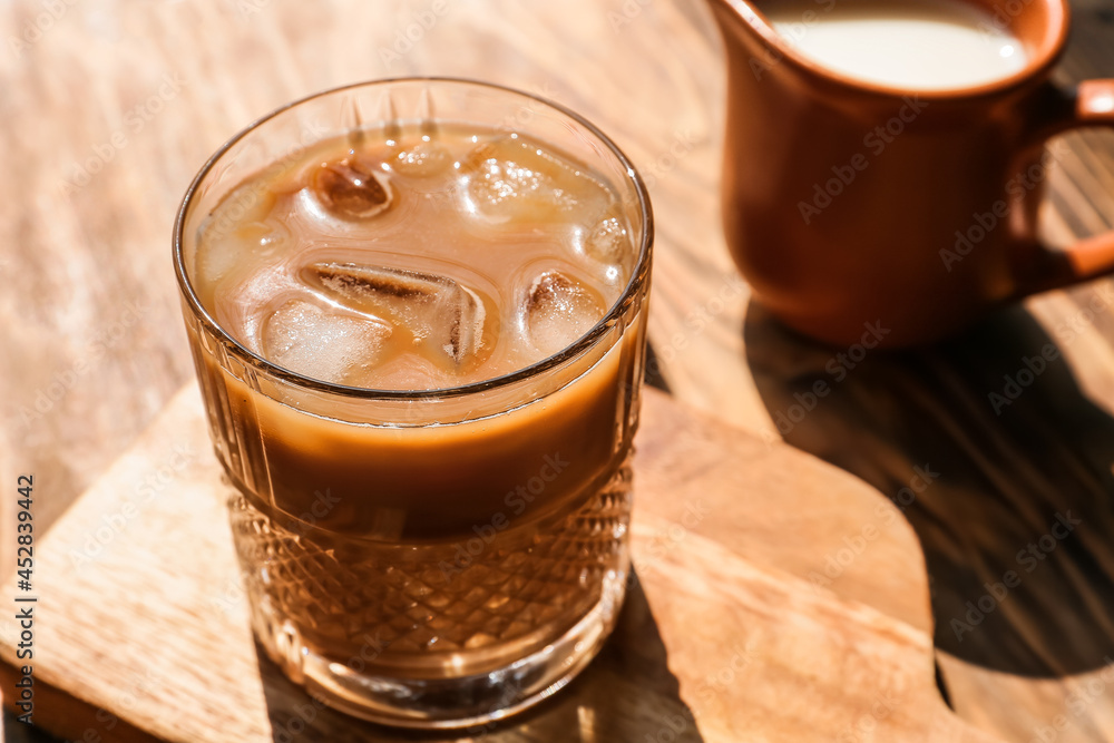 Wooden board with glass of tasty iced coffee on table Wooden board with glass of tasty iced coffee on table