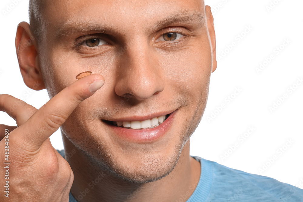 Young man putting in contact lenses on white background Young man putting in contact lenses on white background