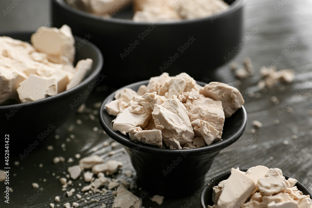 Fototapeta premium Bowls with fresh yeast on dark wooden background