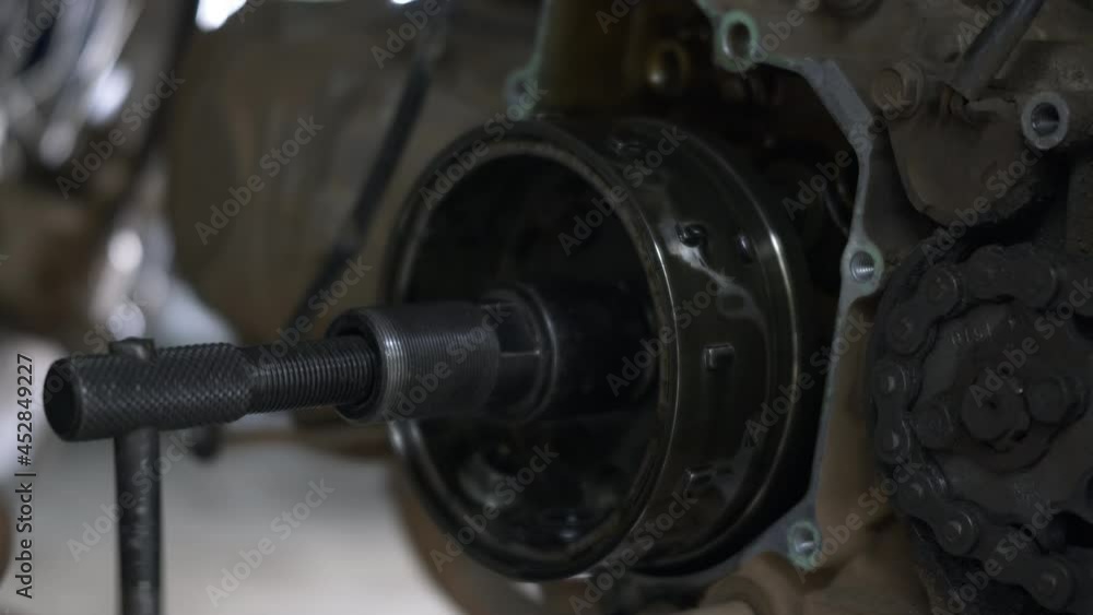 Mechanic removing magnetic wheels unscrew the nut on motorcycle engine mechanic, the motorbike in the shop, automatic motorbike repair Mechanic removing magnetic wheels unscrew the nut on motorcycle engine mechanic, the motorbike in the shop, automatic motorbike repair