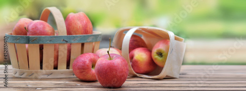 group of red apples in little basket on a wooden table in garden