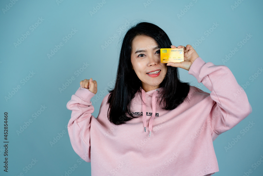 Portrait of an Asian girl wearing a pink shirt. in mobile credit card pose for a photo with a happy face Looking at the camera, behind a gray background in the studio. Portrait of an Asian girl wearing a pink shirt. in mobile credit card pose for a photo with a happy face Looking at the camera, behind a gray background in the studio.