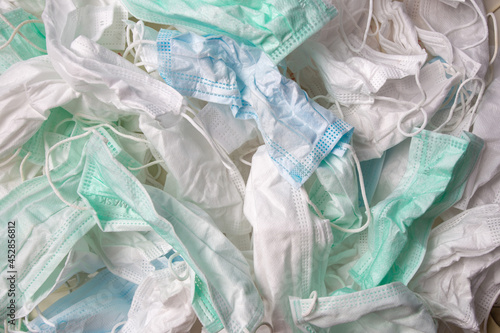 wrinkled and dirty blue, green and white disposable face mask, Group of many used mask. Infectious waste.