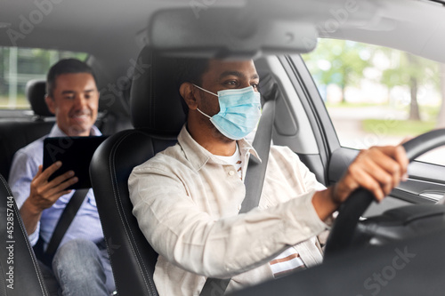 transportation, health and people concept - male passenger with tablet pc computer and indian taxi driver wearing face protective mask for protection from virus disease driving car © Syda Productions
