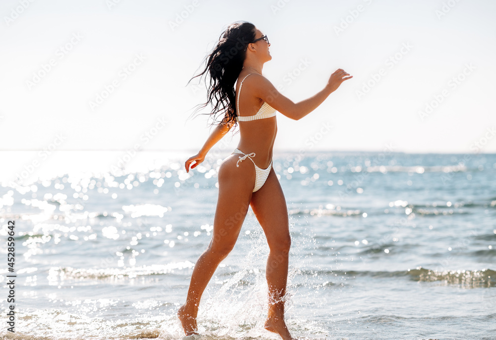 people, summer and swimwear concept - happy smiling young woman in bikini  swimsuit running in water beach Stock-foto | Adobe Stock