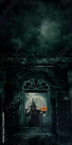Halloween witch with pumpkin monster head standing over ancient castle window  full moon with spooky cloudy sky  Halloween mystery concept
